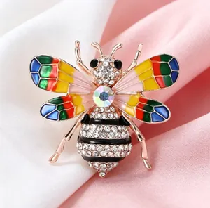 Gros plan d'une broche abeille colorée en émail et strass sur un fond de soie élégant