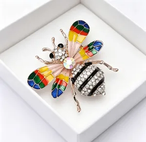 Vue détaillée d'une broche abeille colorée en strass et émail dans une boîte cadeau.