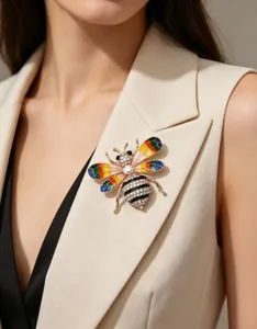Gros plan d'une broche abeille en strass arc-en-ciel sur le revers d'un blazer beige.