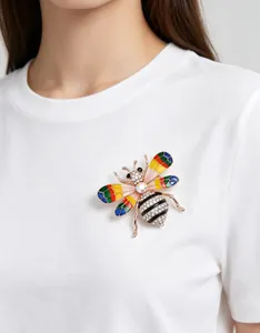 Détail macro d'une broche abeille en strass colorés sur un t-shirt en coton blanc