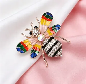 Vue détaillée d'une broche abeille dorée avec ailes en émail coloré et strass