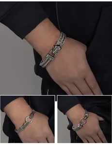 Detail view of men's punk stainless steel bracelet with snake and skull heads.
