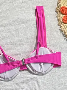 Détail d'un haut de bikini rose vif avec fermeture en métal et bretelles