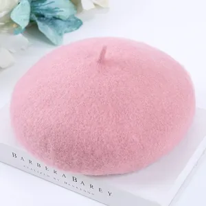 Elegant soft pink wool beret for women displayed on a white vintage book backdrop