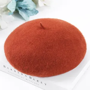 Close-up detail of a warm burnt orange wool beret with soft felt texture and classic design