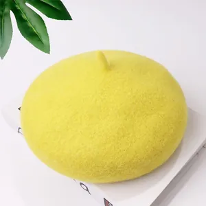 Detailed macro view of a bright yellow wool beret resting on a stylish white book prop.