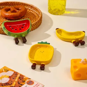 Detailed view of creative fruit-shaped ceramic bowls in watermelon and pineapple designs.