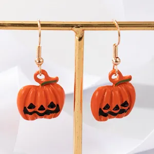 Detailopname van de levendige oranje emaille Halloween pompoen oorbellen op een gouden standaard