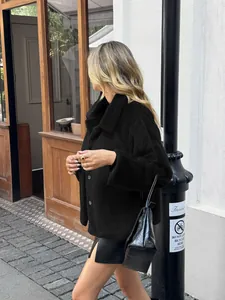 Detail shot of woman wearing a stylish black plush coat with a black leather skirt