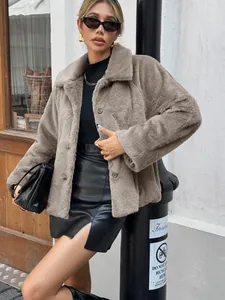 Detail of a stylish brown faux fur jacket worn with a black mini skirt in a street setting.