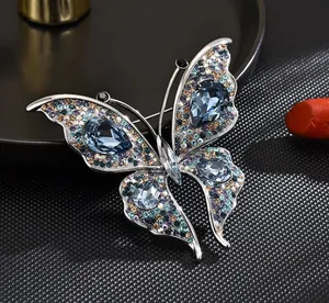 Close-up detail of an elegant crystal butterfly brooch featuring vibrant blue stones.
