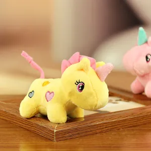 Gros plan d'un adorable porte-clés licorne en peluche jaune avec crinière rose et broderie.