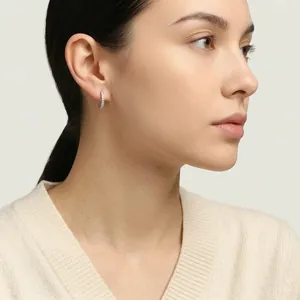 Gros plan d'élégantes boucles d'oreilles créoles en moissanite portées par un modèle