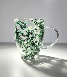Macro detail showing delicate green dried flowers inside double-walled borosilicate glass mug