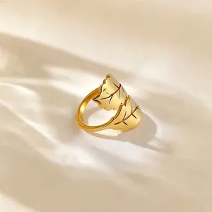 Elegant minimalist titanium steel leaf ring in 18k gold color on soft silk background