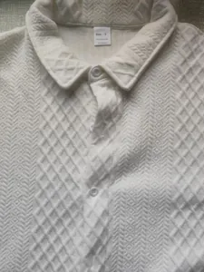 Detailed view of white textured jacquard knitted polo shirt fabric and neck label