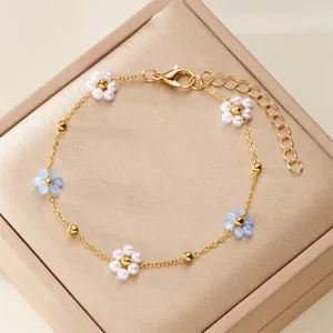 Detailed view of elegant gold chain bracelet with delicate blue and white pearl flowers