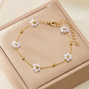 Elegant gold chain bracelet with delicate white pearl flowers on a jewelry gift box.