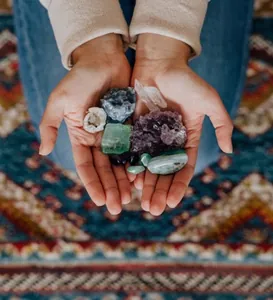 Various raw natural crystals and gemstones held in hands showing natural textures