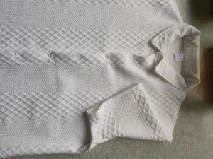 Macro view of white knitted fabric texture on men's short sleeve jacquard polo shirt