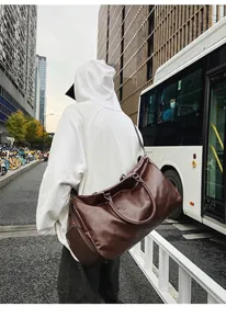 Vintage braune Reisetasche aus PU-Leder mit Schuhfach am Modell präsentiert