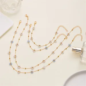 Delicate pearl flower necklace and bracelet set with gold beads on white surface