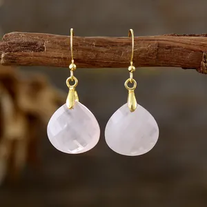Elegant minimalist pink rose quartz teardrop earrings with gold hooks on wooden branch