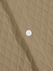 Close-up detail of khaki knit shirt featuring diamond jacquard texture and white button