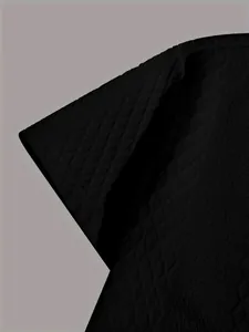 Detail shot of black knitted short-sleeve shirt with textured jacquard pattern.