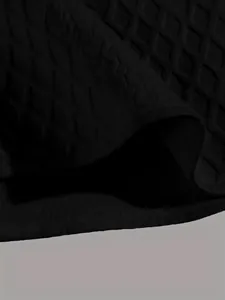 Close-up detail of black knitted fabric with textured jacquard pattern for men's shirt