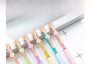 Close-up detail of elegant crystal ballpoint pens with rose gold four-leaf clover clips.