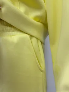 Close-up detail of yellow fleece joggers featuring elastic waistband and side pocket