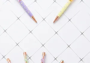 Detailed view of elegant four-leaf clover crystal ballpoint pens on a grid background.