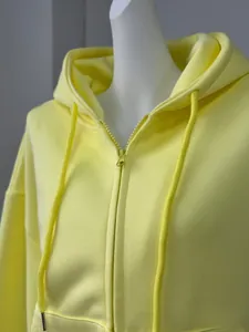 Detailed view of a women's pale yellow zip-up hooded sweatshirt on a mannequin