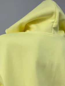 Close-up detail of high-quality soft yellow fabric and hood seams on a casual hoodie