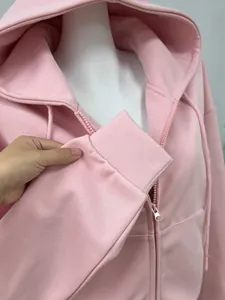 Detailed close-up view of a pink zip-up hoodie showing ribbed cuff and soft fabric texture