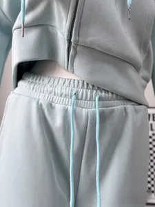 Close-up detail of women's mint green zip-up cropped hoodie and drawstring jogger set