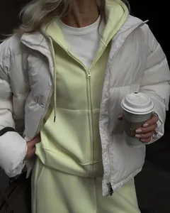 Close-up of women's pale yellow zip-up hoodie set paired with a white puffer jacket