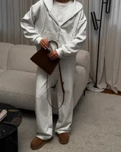 Full lifestyle view of a women's oversized grey zip-up hoodie and matching joggers set
