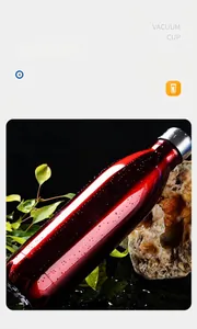 Close-up detail of a red stainless steel vacuum flask with fresh water droplets on rocks