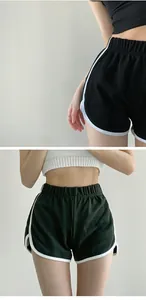 Detail view of women's loose yoga shorts with white contrast piping and elastic waist.