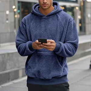 Vue détaillée d'un sweat à capuche en polaire bleue pour homme dans un cadre de rue.