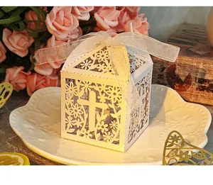 Close-up of laser-cut white wedding favor box with cross and floral pattern detail.