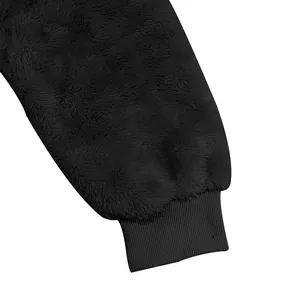 Gros plan sur la texture polaire noire double face et le poignet côtelé d'un sweat à capuche.