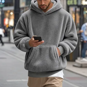 Détail d'un sweat à capuche en polaire grise avec texture pelucheuse et poche kangourou