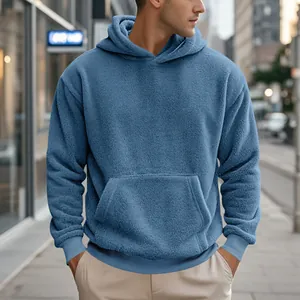 Gros plan sur le tissu texturé et la poche avant d'un sweat à capuche bleu pour homme.