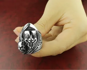 Gros plan d'une bague gothique argentée vintage avec masque rieur et détails de crâne.