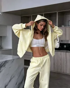Detail view of a yellow oversized zip-up hoodie and matching joggers on a model