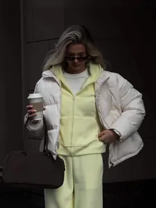 Chic women's pastel yellow zip-up hoodie set with white puffer jacket and brown bag