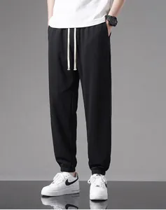 Close-up view of black men's cotton joggers featuring white drawstrings and elastic cuffs